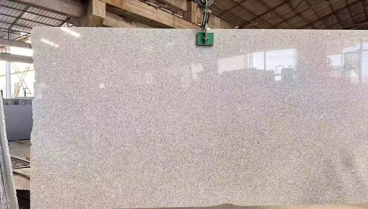 Polished granite slab lifted by overhead crane inside the workshop